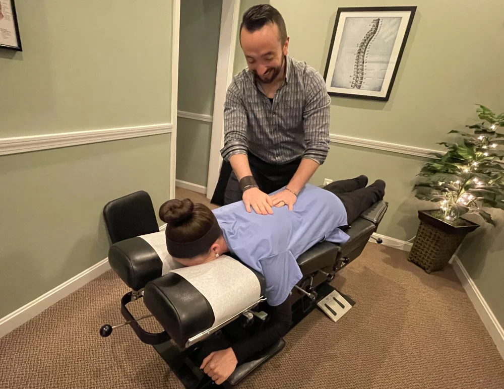 Cornerstone Family Chiropractic Mid-Back Assessment Male chiropractor assesses back of woman laying on treatment table
